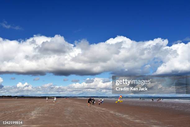 People walk on the West Sands, as parts of Scotland enjoy fine summer weather on July 30 in St Andrews, Scotland. .