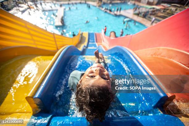 Palestinian girl slides into a swimming pool as they cool off during a hot day in Khan Yunis, in the southern Gaza Strip.