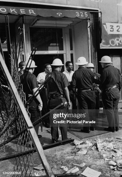 Police officers question protestors outside a pawnbroker's shop at 325 Lenox Avenue, between 127th and 128th Street in Harlem, New York City, July...