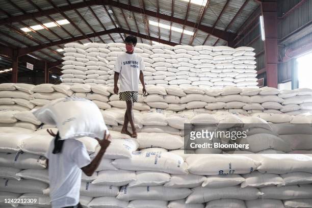 Workers unload sacks of white rice inside an National Food Authority warehouse in Malolos town, Bulacan province, the Philippines, on Friday, July...