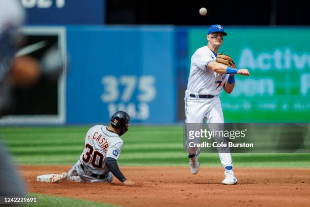 Matt Chapman of the Toronto Blue Jays tries to make a throw to first as Harold Castro of the Detroit Tigers is forced out as Robbie Grossman of the...