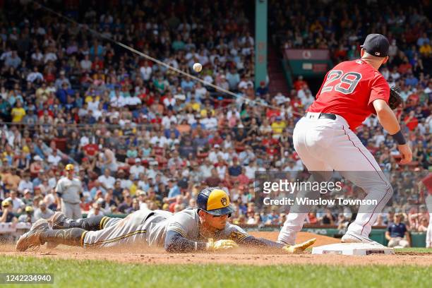 Luis Urias of the Milwaukee Brewers slides safely into first base as Bobby Dalbec of the Boston Red Sox waits for the throw during the sixth inning...