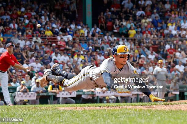 Luis Urias of the Milwaukee Brewers dives head first towards first base for an infield hit as pitcher Garrett Whitlock of the Boston Red Sox tries to...