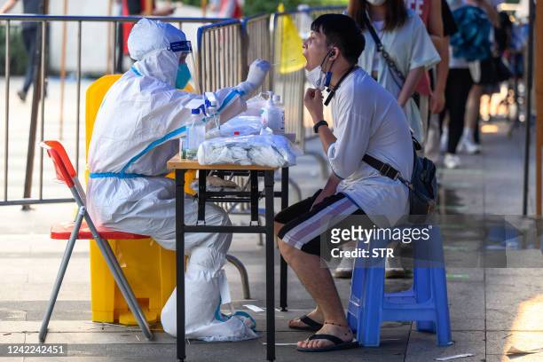 This photo taken on July 31, 2022 shows a health worker taking a swab sample from a man to be tested for the Covid-19 coronavirus at a swab...