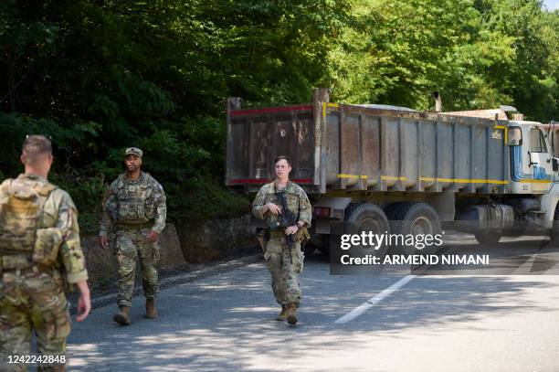 Soldiers serving in Kosovo patrol next to a road barricade set up by ethnic Serbs near the town of Zubin Potok on August 1, 2022. - Kosovo's...