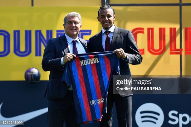Barcelona's new French defender Jules Kounde poses for pictures holding his new jersey with FC Barcelona's Spanish President Joan Laporta during his...