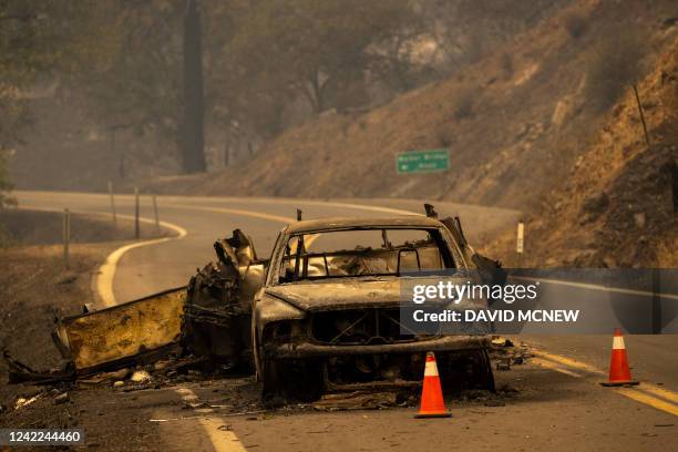 The charred remnants of a car towing a trailer that burned when fire jumped the Klamath River remain on the highway at the McKinney Fire in the...