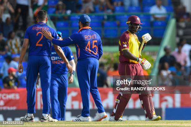 Devon Thomas , of West Indies, walks off the field not out, while Rohit Sharma , of India, cheers on teammates after losing the second T20I match...