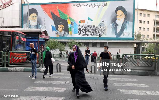 Iranians walk past a billboard displaying Iran's Supreme Leader Ayatollah Ali Khamenei and Ayatollah Ruhollah Khomeini in the capital Tehran, on July...