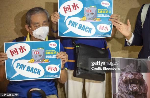 Investors hold placards ahead of an HSBC Holdings Plc informal shareholders meeting in Hong Kong, China, on Tuesday, Aug. 2, 2022. HSBC executives...