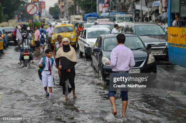 People are seen making their way through a flooded road after heavy rain in Kolkata , India , on 2 August 2022 .