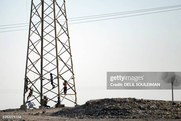 Children play at an electricity tower at a camp for Syrians displaced by conflict near the Syrian northern city of Raqa on August 2, 2022.