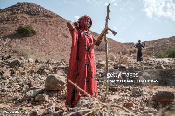 An internally displaced woman cuts wood in the makeshift camp where she is sheltered in the village of Erebti, Ethiopia, on June 09, 2022. - The Afar...