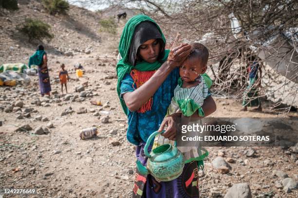 An internally displaced woman washes the face of a child in the makeshift camp where they are sheltered in the village of Erebti, Ethiopia, on June...