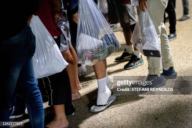 Migrants from Venezuela, who boarded a bus in Del Rio, Texas, hold their belongings in plastic bags after disembarking within view of the US Capitol...