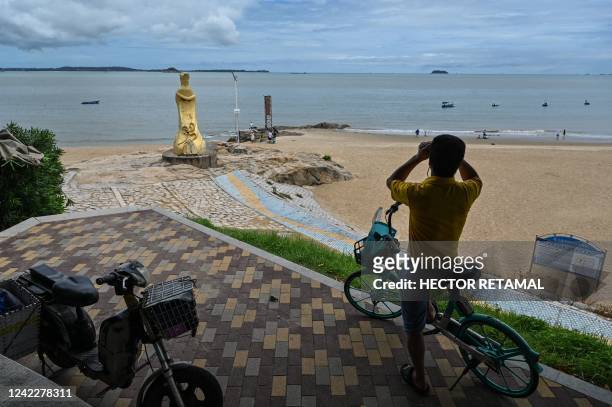 Man looks through a pair of binoculars in Xiamen, across Taiwan's Kinmen Islands on August 3, 2022. - US House Speaker Nancy Pelosi landed in Taiwan...