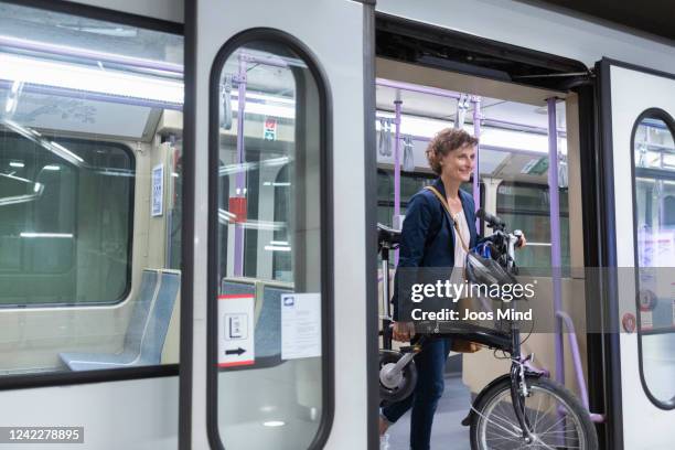 businesswoman carrying bike leaving subway train - folding bike stockfoto's en -beelden