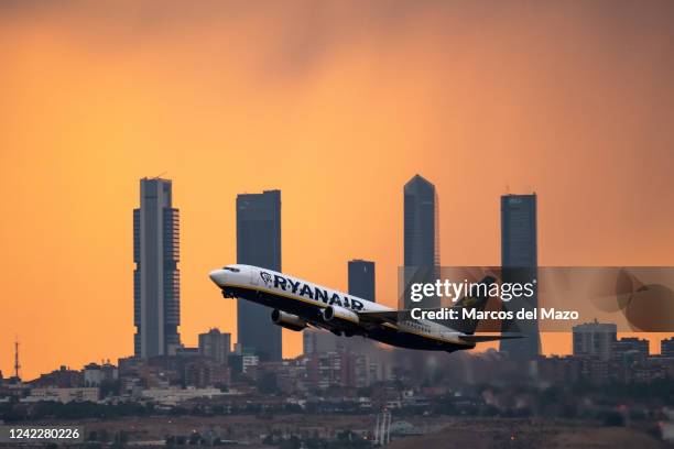 Ryanair airplane departing from Adolfo Suarez Madrid Barajas Airport at sunset during a summer storm, passes by the skyscrapers of the Four Towers...