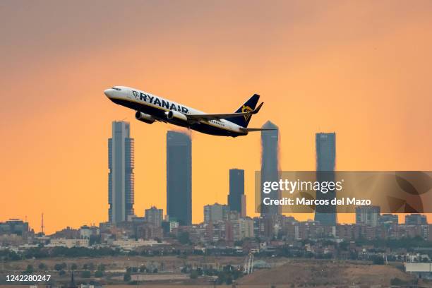 Ryanair airplane departing from Adolfo Suarez Madrid Barajas Airport at sunset during a summer storm, passes by the skyscrapers of the Four Towers...