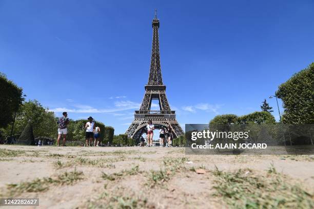 People walk on the dried Champ de Mars in front of the Eiffel tower, on August 3, 2022. France saw its driest July on record, the weather agency...