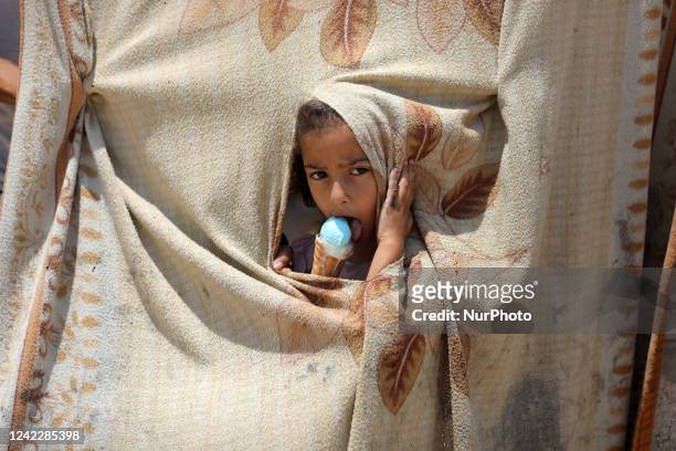 Palestinian girl eats ice cream during a heat wave and lengthy power cuts in a poor neighborhood of Khan Younis, in the southern Gaza Strip, on...