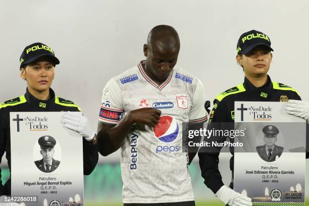 Police officer holds the photo of a fellow police officer killed in the Clan del Golfo's gun plan and in the middle is Adrian Ramos player of America...