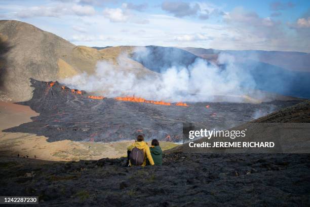 People look at the lava flowing at the scene of the newly erupted volcano at Grindavik, Iceland on August 3, 2022. A volcano erupted on August 3,...