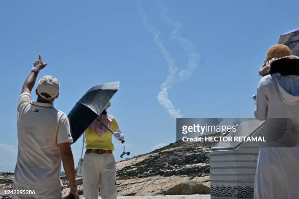 Smoke trails from projectiles launched by the Chinese military are seen as tourists look on from Pingtan island, one of mainland China's closest...