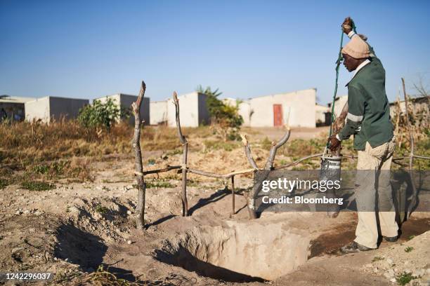 Resident hoists a bucket of water from a well to water his garden in Bulawayo, Zimbabwe, on Thursday, June 23, 2022. After more than a century of...