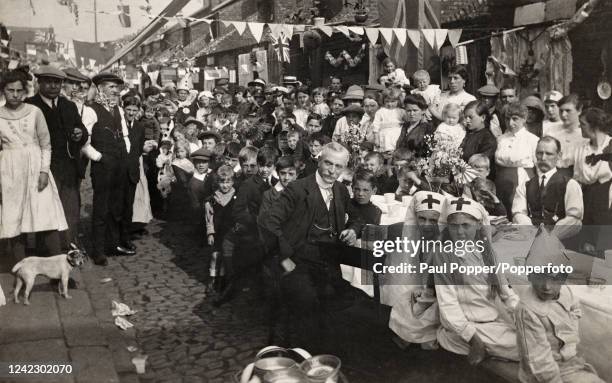 Vintage postcard featuring a peace celebration and street party with multi-generational participants, some in fancy dress, in Newcastle, following...
