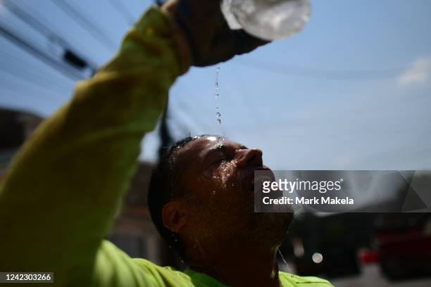 Construction worker Felipe Campuzano pours water on his face to cool off as he digs a sanitation pipe ditch during a heatwave on August 4, 2022 in...