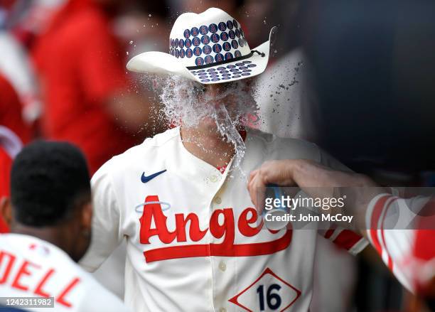 Mickey Moniak of the Los Angeles Angels is congratulated for his home run with a cowboy hat and cup of water to the face in the ninth inning against...