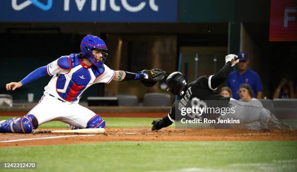 Luis Robert of the Chicago White Sox beats the tag by Jonah Heim of the Texas Rangers to score a run during the third inning at Globe Life Field on...