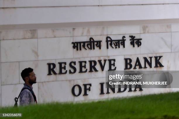 Man walks past a sign of the Reserve Bank of India in Mumbai on August 5, 2022. India's central bank on August 5 hiked interest rates for the third...