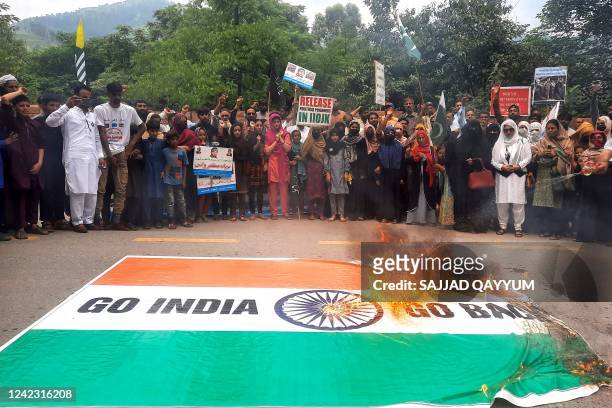 People of Pakistan-administered Kashmir gather beside a burning national flag of India during a protest against the scrapping of Article 370 of Jammu...