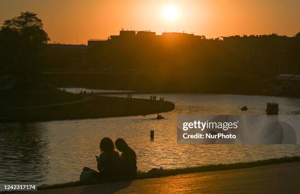 People enjoy the sunset on the banks of the Vistula River near Wawel in Krakow. On Thursday, August 04 in Krakow, Lesser Poland Voivodeship, Poland.