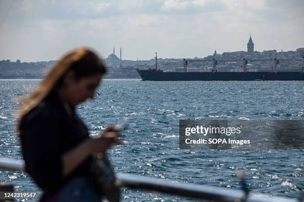 Woman is seen staring at her mobile phone with the dry cargo ship, Razoni, carrying a cargo of 26,527 tons of corn in the background. The Razoni...