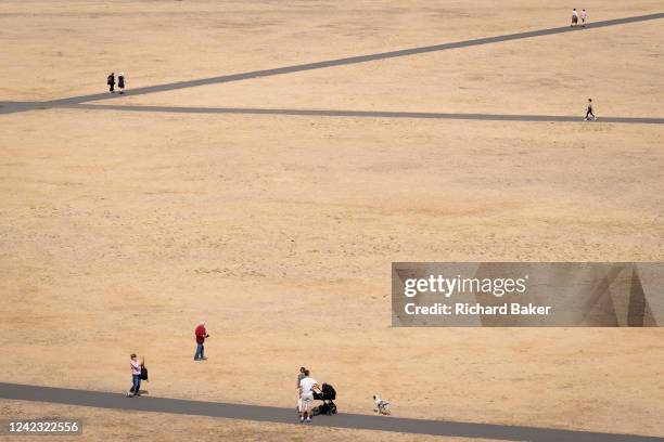 Park users walk through a parched grass landscape in Greenwich Park as the UK's heatwave and drought continues into August with little rain having...