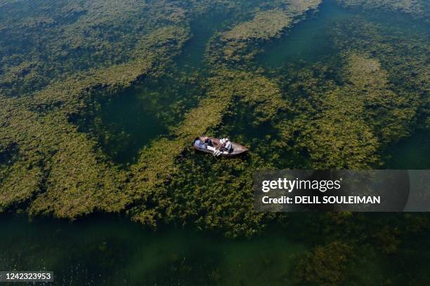 An aerial picture taken by drone on August 5 shows fishermen on the Euphrates river in low water levels in the western country side of Raqa on August...