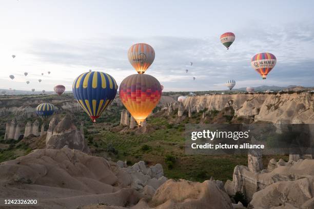 June 2022, Turkey, Göreme: Hot air balloons flying at sunrise in front of a rock plateau. Photo: Sebastian Kahnert/dpa