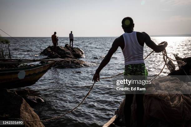 Fishing boats arrive at a dock on the edge of Lake Victoria at dawn as people gather to buy the nights catch, on August 5, 2022 in Kisumu, Kenya. The...