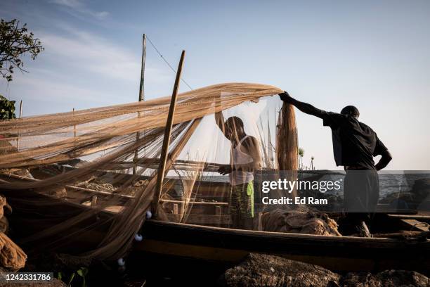 Men prepare fishing nets on the edge of Lake Victoria as they prepare to go and fish, on August 5, 2022 in Kisumu, Kenya. The fishing industry, which...