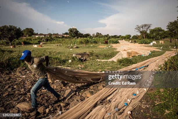 Men prepare fishing nets on the edge of Lake Victoria as they prepare to go and fish, on August 5, 2022 in Kisumu, Kenya. The fishing industry, which...