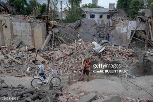 Local resident pushes her bicycle through damaged buildings in Toretsk, eastern Ukraine, on August 5 amid the Russian invasion of Ukraine. - They...