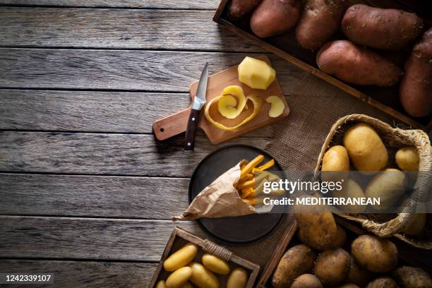 frites aardappels op een rustieke houten raadslijst met ruwe aardappels rond - kegel stockfoto's en -beelden