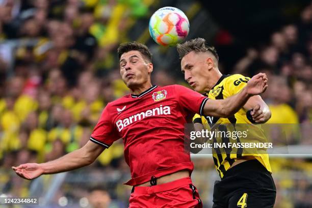 Leverkusen's Czech forward Patrik Schick and Dortmund's German defender Nico Schlotterbeck both jump to head the ball during the German first...