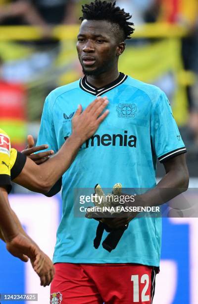 Leverkusen's Burkinabe defender Edmond Tapsoba puts on the gloves to go in goal after Leverkusen's Finnish goalkeeper Lukas Hradecky was sent off by...