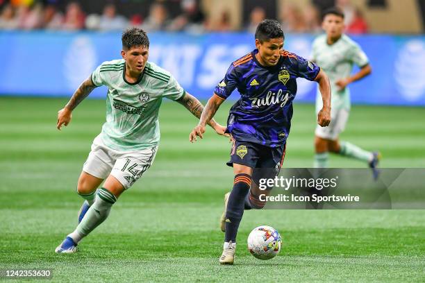 Seattle forward Raul Ruidiaz moves past Atlanta midfielder Franco Ibarra during the MLS match between Seattle Sounders FC and Atlanta United FC on...