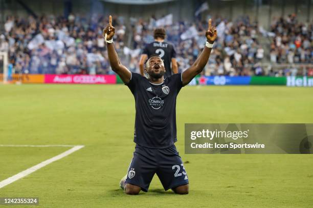 Sporting Kansas City forward William Agada kneels and points to the sky after scoring a goal in the first half of an MLS match between Sporting KC...