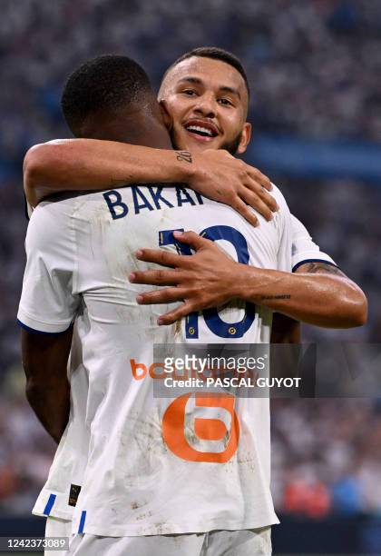 Marseille's Colombian forward Luis Suarez is congratulated by his teammate Marseille's Congolese forward Cedric Bakambu after scoring a goal during...
